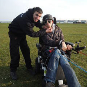 man with woman in wheelchair flying a kite