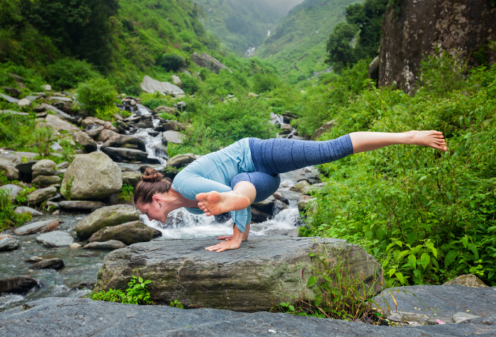 woman doing yoga by a stream